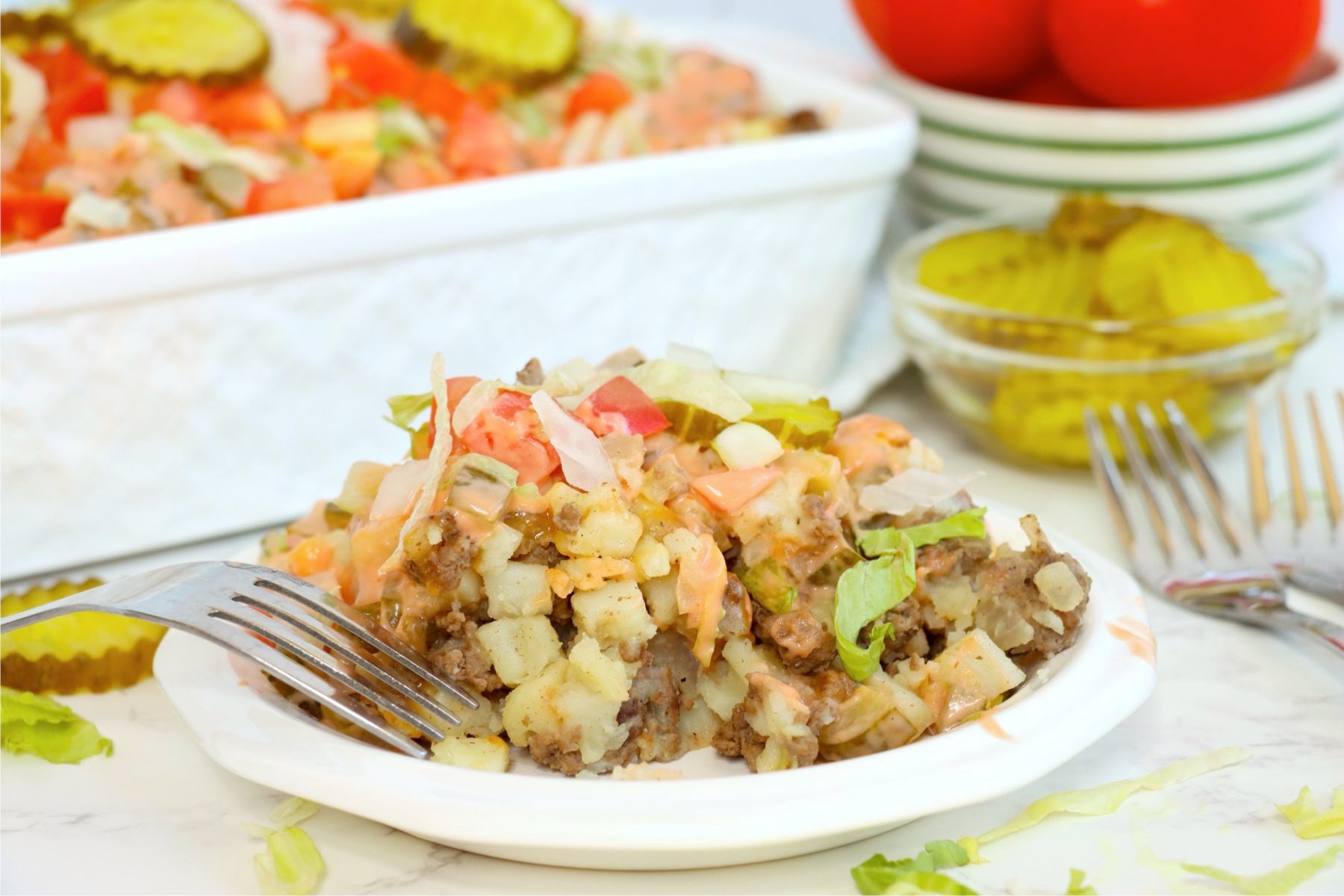 Serving of Big Mac casserole on a white plate with sauce and toppings.