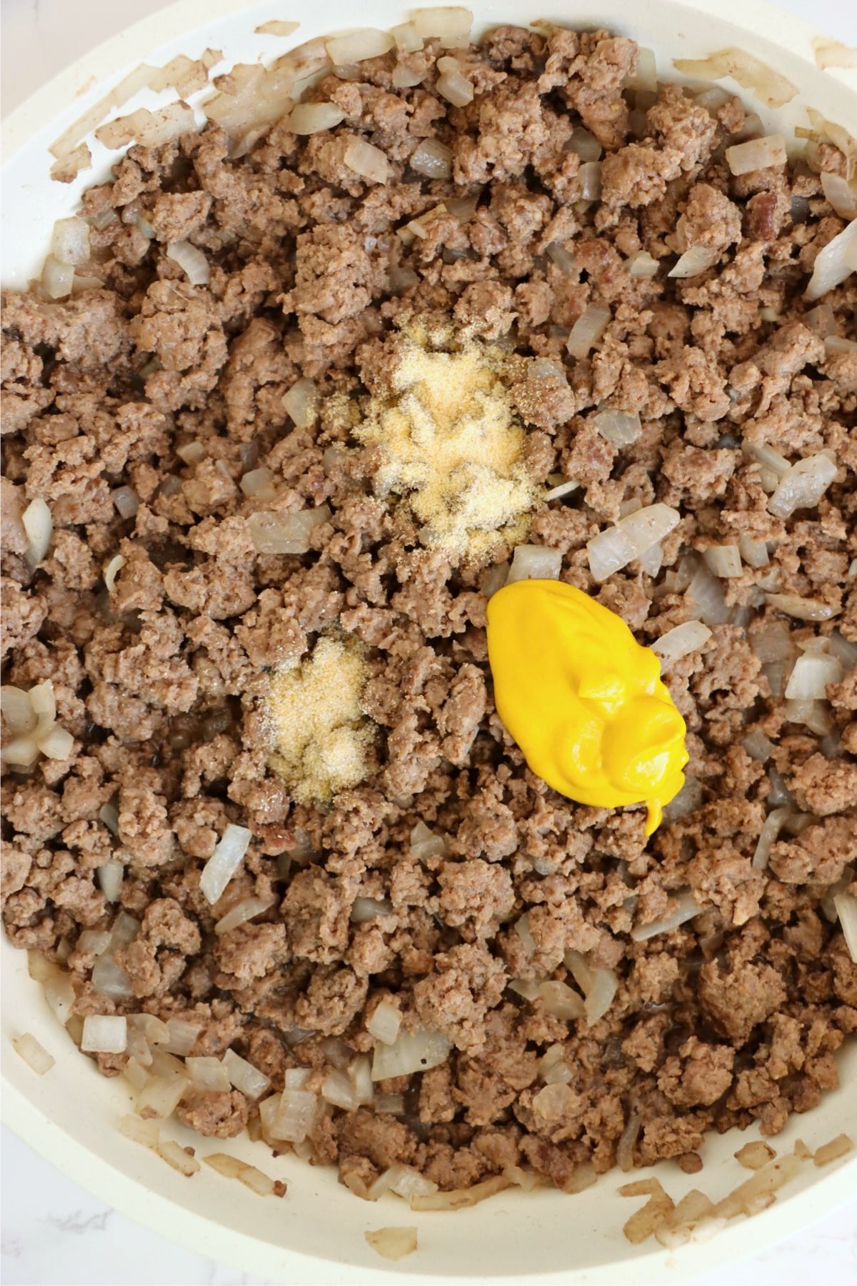 Cooked ground beef with onions and seasonings in a skillet.
