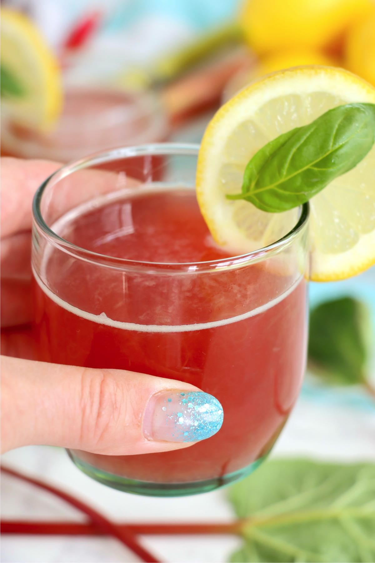 Hand holding a rhubarb cordial drink.