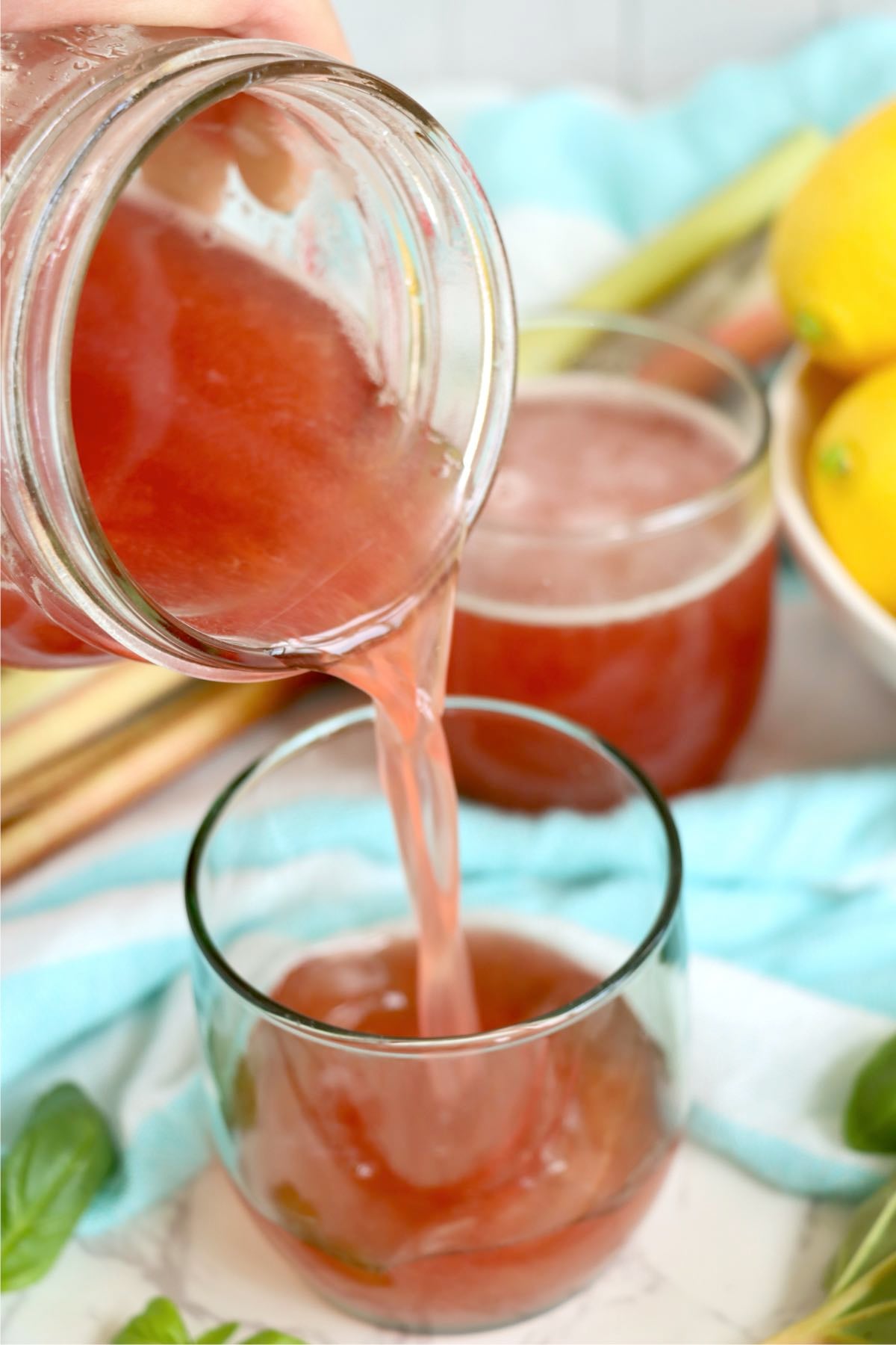 Homemade rhubarb cordial being poured into a serving glass.