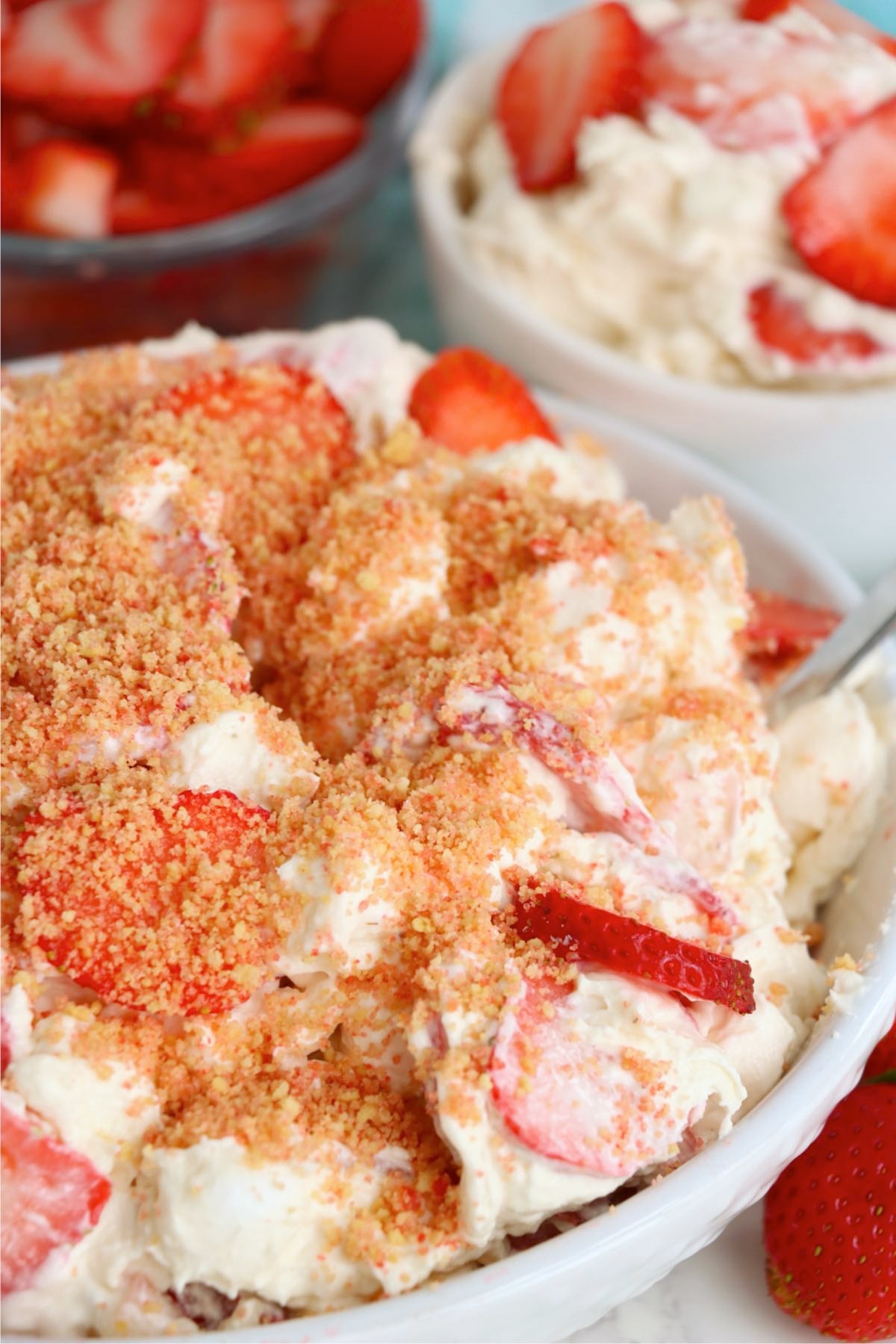 Bowl of creamy strawberry fluff topped with Golden Oreo crunch and fresh sliced strawberries.