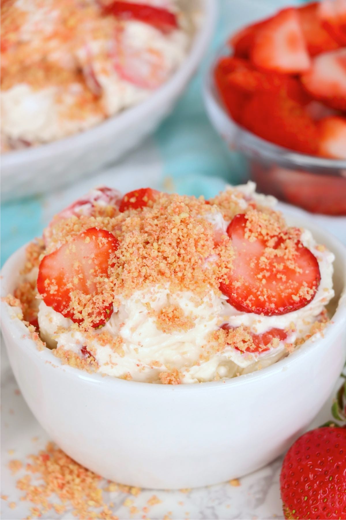 Bowl of no-bake strawberry fluff dessert served with sliced strawberries.
