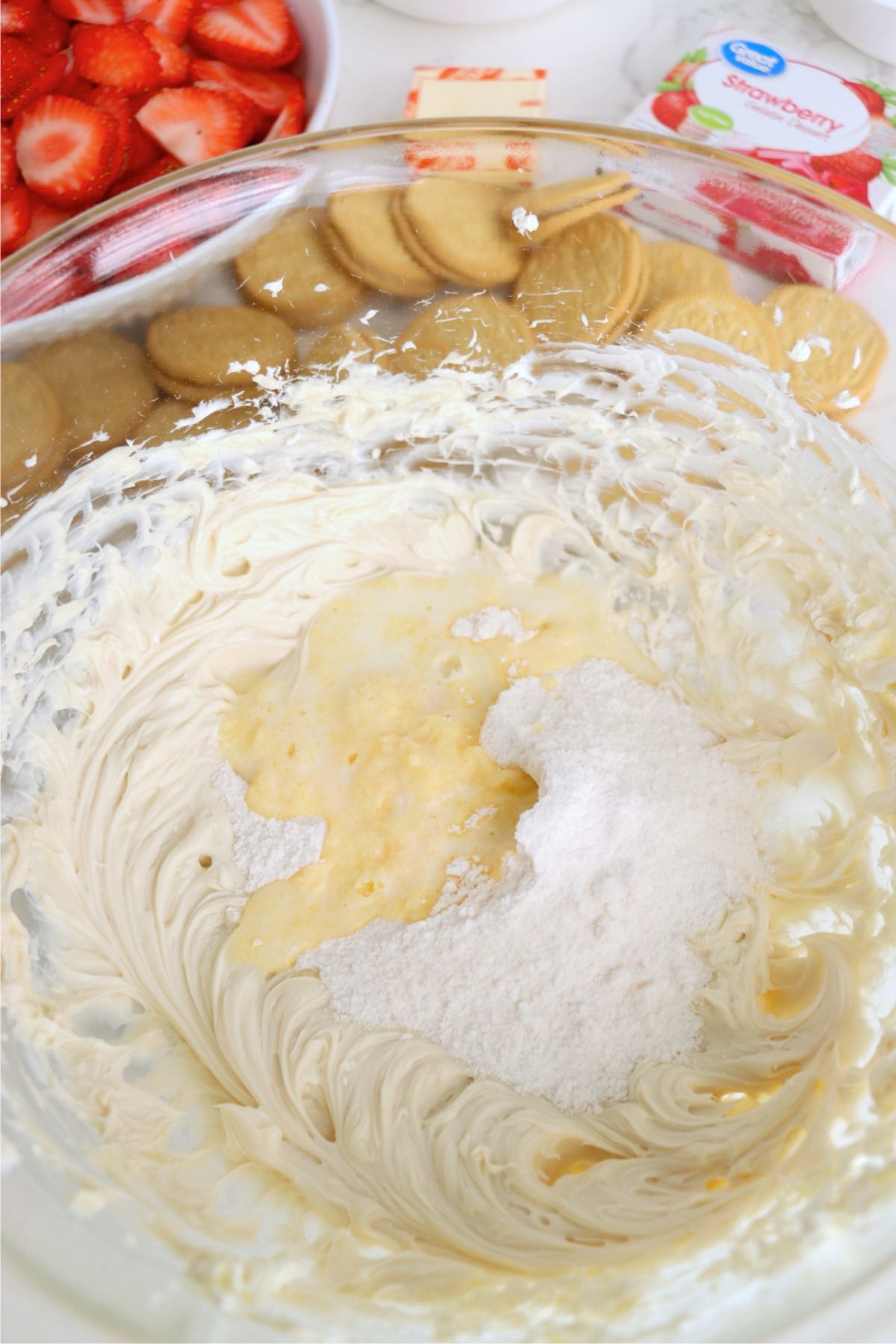 Cheesecake pudding mix being blended into cream cheese mixture until creamy.