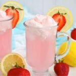 Pink lemonade with fluffy whipped topping, fresh strawberries and lemon slices.
