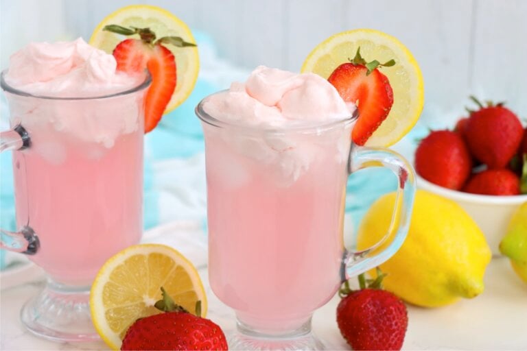 Pink lemonade with fluffy whipped topping, fresh strawberries and lemon slices.