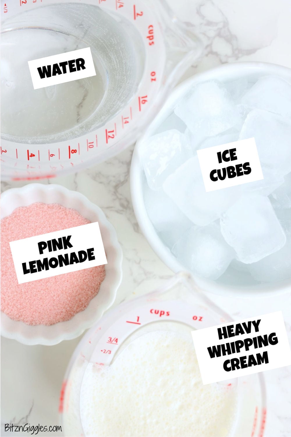 Water, heavy whipping cream, pink lemonade mix and ice cubes laid out on a marble surface.