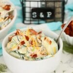 Creamy cucumber half-moons layered with crisp bacon, shredded cheddar and fresh dill in a white bowl.