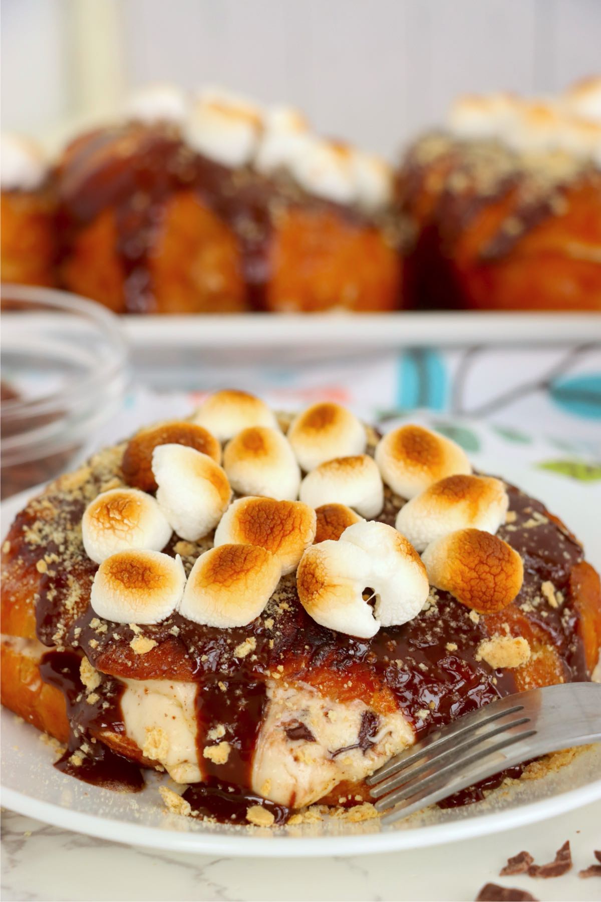Plated croissant with creamy filling, chocolate drizzle, graham crumbs and toasted mini marshmallows.