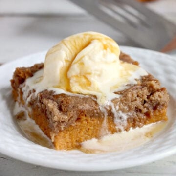 A slice of pumpkin dump cake topped with vanilla ice cream and caramel sauce.