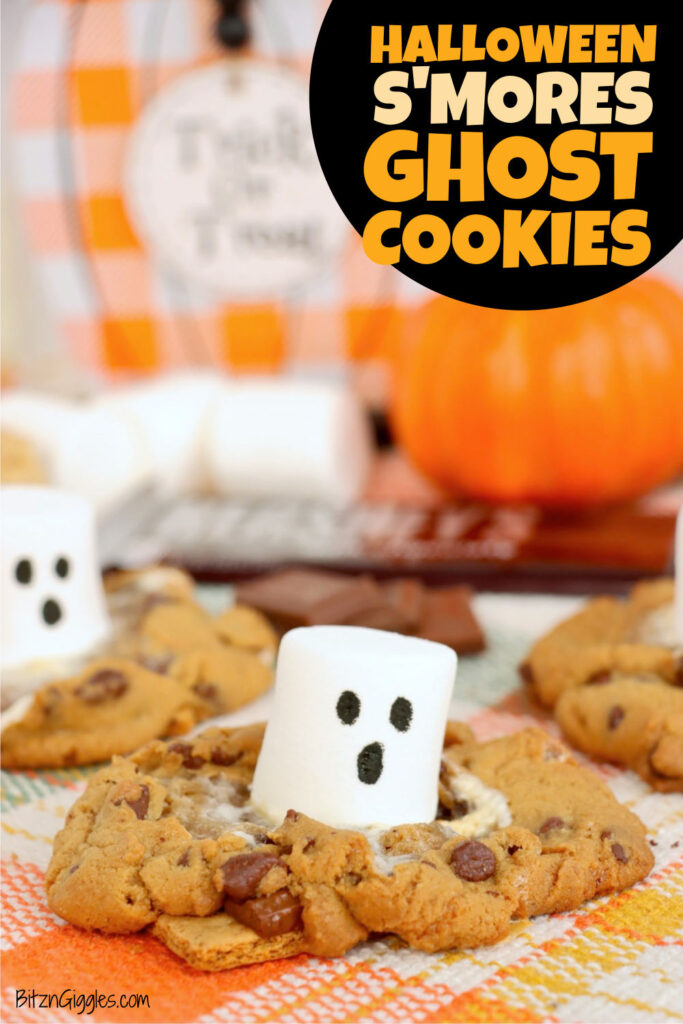 Marshmallow ghost sitting in a golden brown chocolate chip cookie with melted marshmallow and chocolate, surrounded by Halloween decorations.