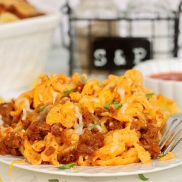 Cheesy ground beef and egg noodles with melted cheese and fresh green garnish.